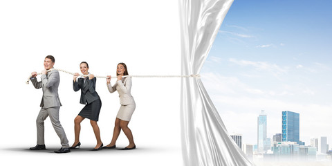 Young businesspeople working in collaboration and pulling white advertisement banner