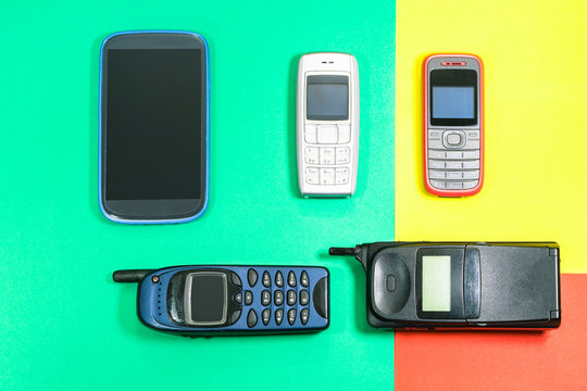 Old mobile phones used and outdated on colorful pop style background top view image - Concept of technological development in communications devices                             