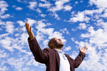 African American man stading outside with open arms.