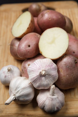 Pile of potatoes with garlic on wood board with black background