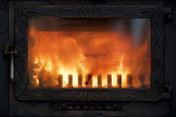 Nahaufnahme eines schönen Feuers in einem alten Ofen mit glänzender Kaminscheibe