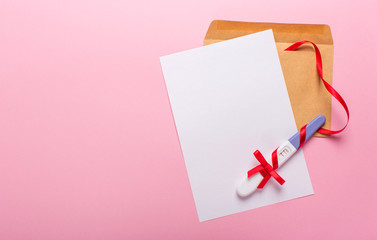 letter with a positive pregnancy test on a pink background