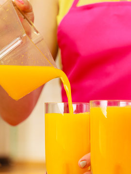 Woman pouring orange juice drink in glass