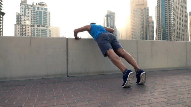 Young man doing push-ups on wall in city, super slow motion 240fps
