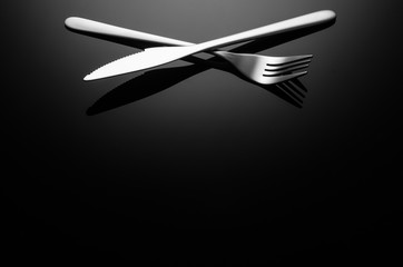 Black food background. Stainless steel, modern silverware on black background with reflection. Image with copy space. Symbol or concept for diners, cafes and good food competitions and festivals