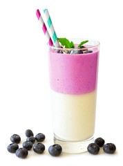 Layered blueberry and coconut smoothie with mint and scattered berries on a white background