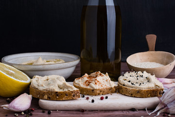 Sandwiches with hummus and few ingredients in rustic light.