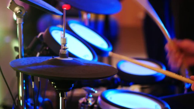 Young man playing electronic drums on stage. Concert. Neon light.