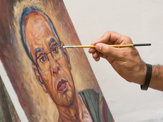 Closeup artist hand holding paint brush painting portrait of asi