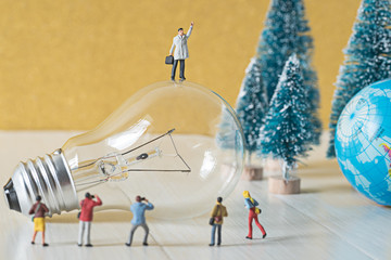 business miniature standing on a top of vintage light bulb