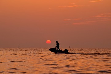 Silhouette of man driving jetski on the sea with during sunset