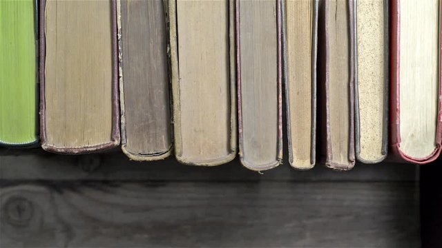 A man's hand picks up a book from a bookshelf
