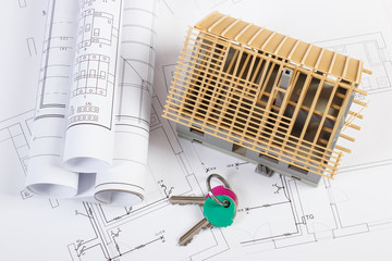 Home keys, small house under construction and electrical drawings, building home concept