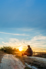 Traveler resting on a country road during sunset