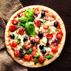 Hot pizza with Pepperoni Sausage on a dark background, top view.