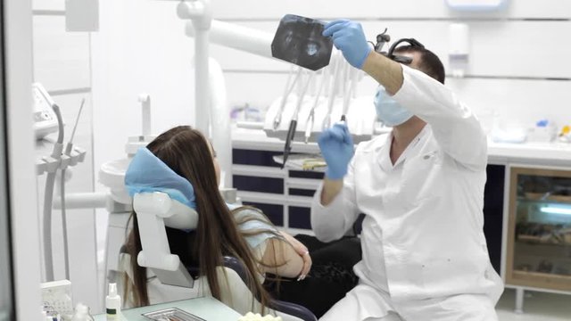 Dentist shows a patient x-rays of the teeth in the dental office