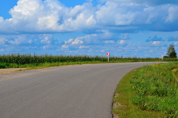 Asphalt road marked by dangerous turn road signs. View of the road in the summer sunny day