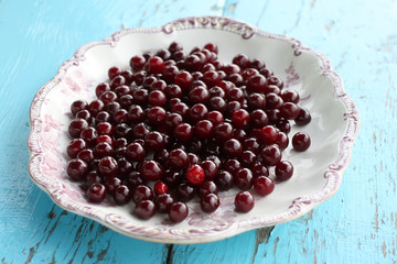 Fresh ripe cherries in a plate on wooden background