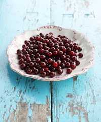 Fresh ripe cherries in a plate on wooden background