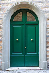 Green exterior door entrance with briks wall background.