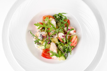 Salad with shrimp, tomatoes, cheese and rocket salad on a plate on a white background, top view closeup