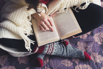 girl reading a book in a warm blanket