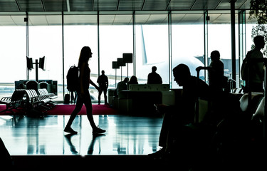 Silhouette of young woman going in waiting hall.