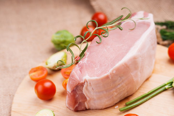 Raw pork on cutting board and vegetables 