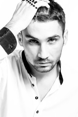 Man with rosary with a cross straightens hair. Close-up portrait. High key.