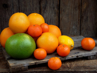 composition of citrus on wooden background: tangerines, oranges, sweetie, lemon. Side view