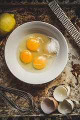 raw eggs in a bowl, whisk lemon and grater