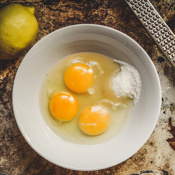 raw eggs in a bowl, whisk lemon and grater