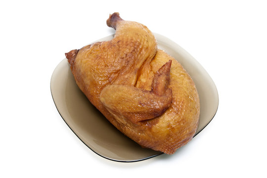 half smoked chicken carcass on a plate on white background