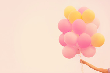 Female hand holding colorful balloons against sky background
