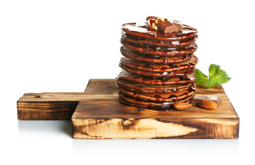 Tasty pancakes with chocolate and sweet sauce on wooden board, isolated on white