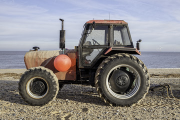 Profile of red tractor on the beach