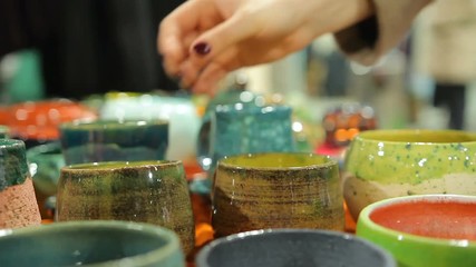 Lady choosing decorative handmade pottery bowls at ceramic store, shopping