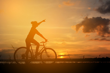 Obraz premium Silhouette of happy women with bicycle in nature at the sky sunset