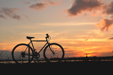 Silhouette bicycle near the river in nature at sky sunset color of vintage tone