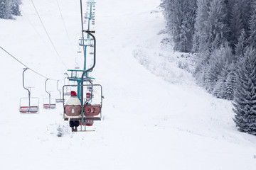 Skiers on ski-lift in snow mountains at winter day. 
