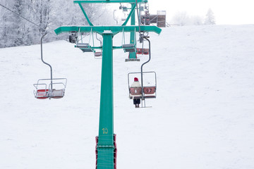 Skiers on ski-lift in snow mountains at winter day. 