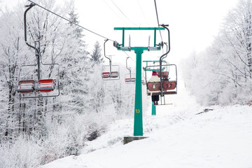Fototapeta na wymiar Skiers on ski-lift in snow mountains at winter day. 