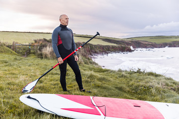 Man with paddle board over the cliffs