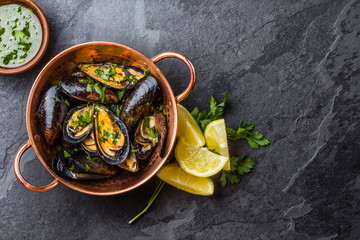 Mussels in copper bowl, lemon, herbs sauce and white wine.