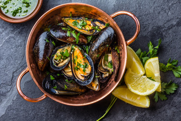 Fototapeta na wymiar Mussels in copper bowl, lemon, herbs sauce and white wine.
