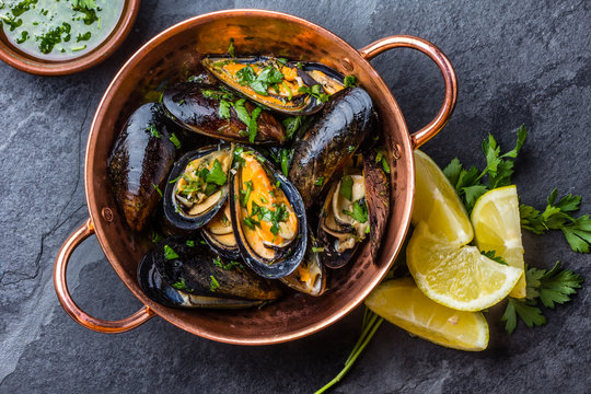 Mussels in copper bowl, lemon, herbs sauce and white wine.