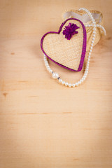 Elegant valentine background with white pearls and gift box shaped of heart on wooden background. Empty space for text
