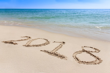Year 2018 written at the sand beach with sea wave water
