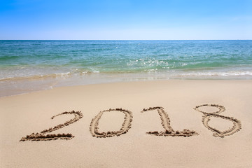 Year 2017 written at the sand beach with sea wave water