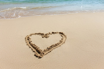 Heart shape, love symbol written at the sand beach